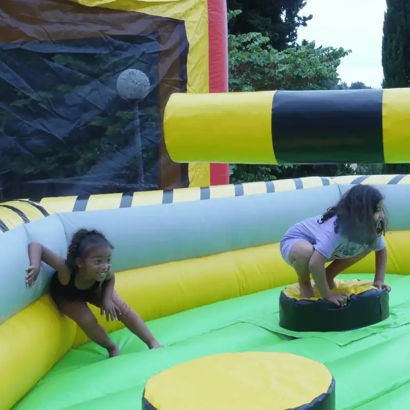 deux enfants accroupis dans une location de faucheuse gonflable