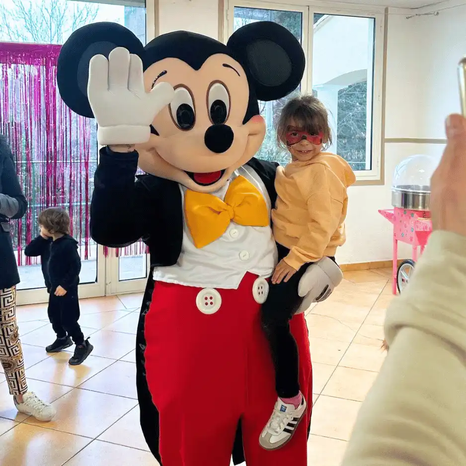 mascotte mickey mouse avec un enfant dans les bras